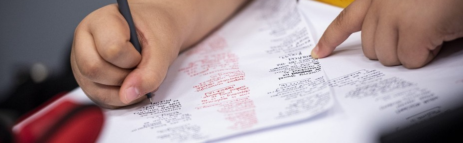 Hands writing and annotating debate briefs with pen, highlighting arguments and evidence